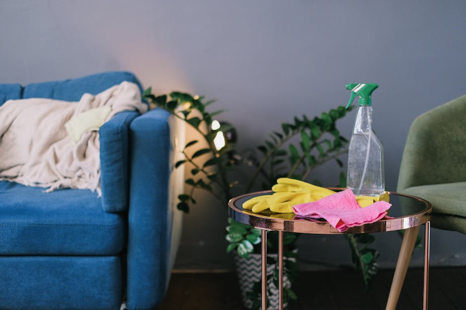 A close-up view of a contemporary living room corner featuring a blue fabric sofa with a slightly disheveled cream-colored blanket draped over its armrest, positioned next to a small round side table 